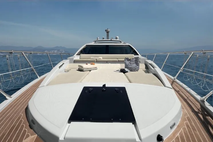 Luxury Azimut 55 power yacht cruising on the turquoise waters of Sardinia with a scenic Mediterranean coastline in the background.