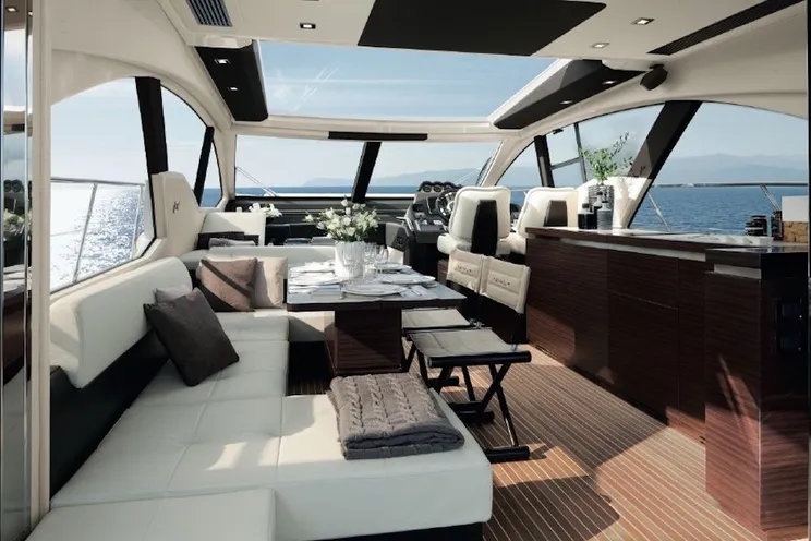 Luxury Azimut 55 power yacht cruising on the turquoise waters of Sardinia with a scenic Mediterranean coastline in the background.